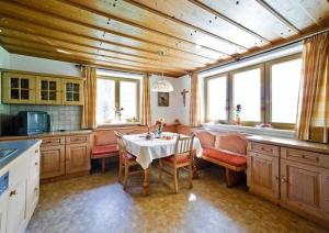 a kitchen with a table and chairs and windows at Pension Ederhof in Jochberg