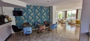 una sala de estar con sillas azules y una pared con papel pintado floral en Aura Living Hotel, en Rímini