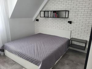 - une chambre avec un lit et un mur en briques blanches dans l'établissement Apartmán Pekná Vyhliadka - Vila Vlasta, à Vysoke Tatry - Horny Smokovec
