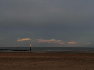 a beach with two light posts and the ocean at La Chambre du 21 in Trouville-sur-Mer
