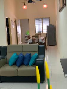 a couch with blue pillows in a living room at ZillQayyim Homestay in Seri Iskandar +24 photos