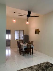 une salle à manger avec une table, des chaises et un ventilateur de plafond dans l'établissement ZillQayyim Homestay, à Seri Iskandar