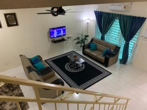 sala de estar con 2 sofás y TV en ZillQayyim Homestay, en Seri Iskandar