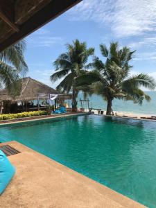 a swimming pool next to a beach with palm trees at doublep in Ban Phlong Sawai