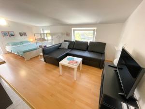 a living room with a black couch and a bed at Apartmani Tanja in Dramalj