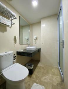 a bathroom with a toilet and a sink and a mirror at Hans Inn Batam in Nagoya