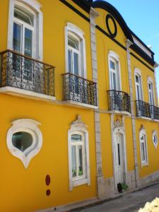 un edificio amarillo con balcones en una calle en HI Tavira – Pousada de Juventude, en Tavira