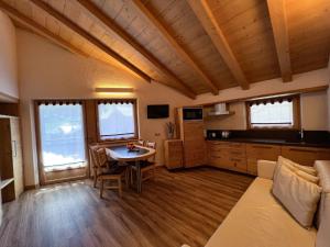 sala de estar con mesa, sofá y cocina en Casa Meta, en Livigno