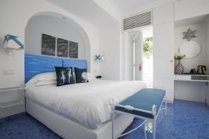 a bedroom with a blue and white bed and a sink at Relais Maresca Luxury Small Hotel & Terrace Restaurant in Capri