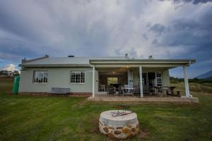 a white house with a patio and a table at Appelsbosch Guest Farm in Swellendam
