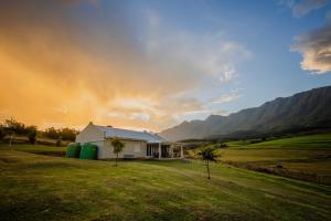 a house in a field with mountains in the background at Appelsbosch Guest Farm in Swellendam