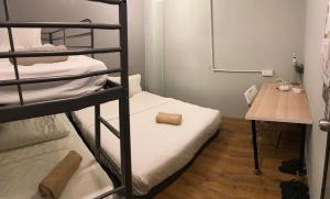 a small room with two bunk beds and a table at GRAYHAUS SOHO Ipoh in Ipoh