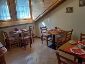 a dining room with two tables and chairs and windows at B&B Piazzi di Katia in Caderzone Terme