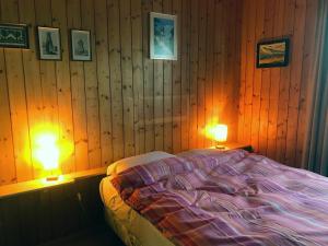 a bedroom with wood paneling and a bed with two lamps at Les Tchaipus in Nendaz