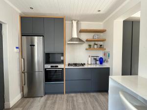 a kitchen with gray cabinets and a stainless steel refrigerator at Cowrie Cottage Self Catering in Cape Town