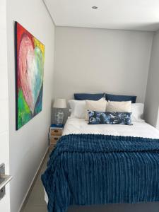 a bedroom with a bed with a blue blanket at Cowrie Cottage Self Catering in Cape Town