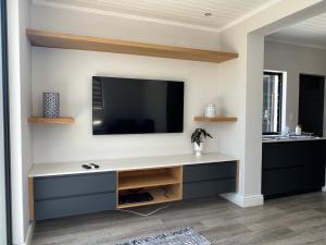 a living room with a tv on a wall at Cowrie Cottage Self Catering in Cape Town