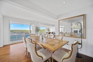 comedor con mesa, sillas y espejo grande en 42 Loves Bay 5 Bedroom Sea cliff View House with Pool, en Kiama