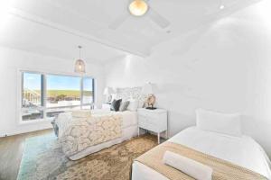 Un dormitorio blanco con dos camas y una ventana. en 42 Loves Bay 5 Bedroom Sea cliff View House with Pool, en Kiama 61 fotos más