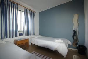 オエイラスにあるHI Oeiras – Pousada de Juventudeのベッドルーム1室(ベッド2台付)、壁にギターが備わります。