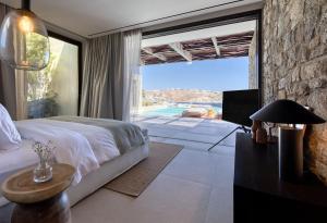 1 dormitorio con cama y ventana grande en Untold Mykonos, en Mykonos ciudad