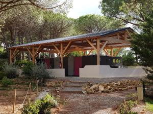 a wooden pavilion in a park with trees at Ushuaïa Villages Camping Figurotta in Bizanet