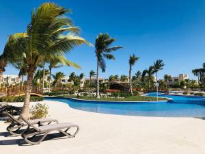a pool with palm trees and lounge chairs at a resort at 1-Bedroom on Forest Island & Oceanside View in Salalah