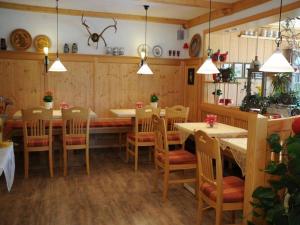 ein Esszimmer mit Tischen, Stühlen und Hängelampen in der Unterkunft Pension Einsiedelei in Zwiesel