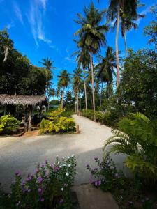 a road with palm trees and flowers in front of a house at Elena Garden Resort and Restaurant in Trincomalee