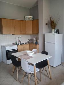a kitchen with a table and chairs and a white refrigerator at Kamares View in Ayeranós
