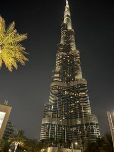 ein hohes Gebäude mit einem sehr hohen Turm in der Nacht in der Unterkunft OMAR Vacation in Dubai