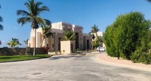 a street in front of a building with palm trees at 1-Bedroom in Forest Island & Oceanside View in Salalah