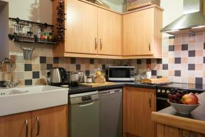 a kitchen with wooden cabinets and a sink and a dishwasher at The Barn - Yorkshire Coast Holiday Lets in Whitby