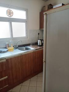eine Küche mit einem Kühlschrank, einer Spüle und einem Fenster in der Unterkunft OMAR Vacation in Dubai