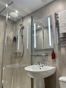 a bathroom with a sink and a shower with a mirror at Lacet House in Ambleside