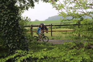 a child riding a bike next to a fence with a horse at Tiny House Kotten Kunterbunt in Nottuln