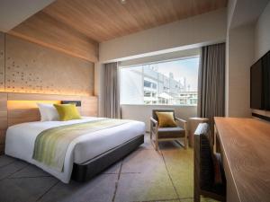 a bedroom with a bed and a desk and a window at Hotel Metropolitan Yamagata in Yamagata