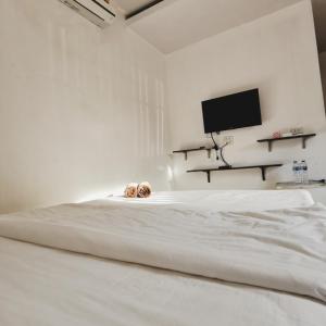 a white bed in a white room with a television at De​ Lanta place in Ko Lanta