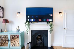 un soggiorno con camino e TV a schermo piatto sopra di esso di Meadowbank Residence 3bed free parking a Edimburgo