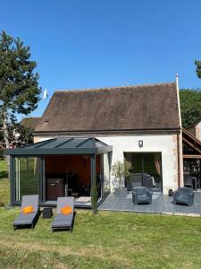 a house with a patio with chairs and a roof at Maison au cœur des étangs de Sologne avec SPA , Domaine de Sainte-Marie in Ardon