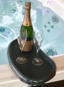 dos copas de vino y una botella de champán en una bañera en Maison au cœur des étangs de Sologne avec SPA , Domaine de Sainte-Marie, en Ardon