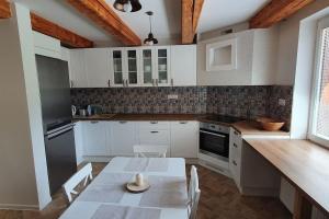 a kitchen with white cabinets and a table with chairs at Chata Damal pri Liptovskej Mare in Žiar