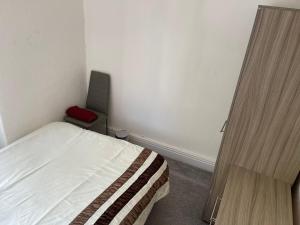 a small bedroom with a bed and a red chair at Ashdale Guest House Liverpool in Liverpool