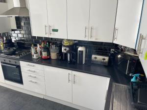 a kitchen with white cabinets and a black counter top at Ashdale Guest House Liverpool in Liverpool