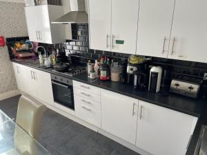 a kitchen with white cabinets and a black counter top at Ashdale Guest House Liverpool in Liverpool