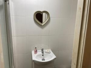 a bathroom with a sink and a heart shaped mirror at Ashdale Guest House Liverpool in Liverpool