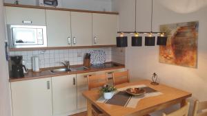eine Küche mit einem Holztisch und eine Küche mit weißen Schränken in der Unterkunft Haus Christianenhöhe App 40 in Westerland