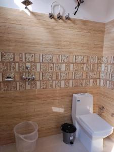 a bathroom with a toilet and a tile wall at Tatsat Hostel in Rishīkesh