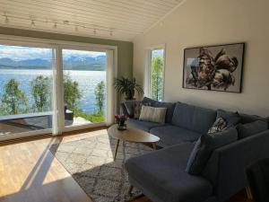 a living room with a blue couch and a large window at Great house with amazing location!!Sea & mountain view! in Kvaløya