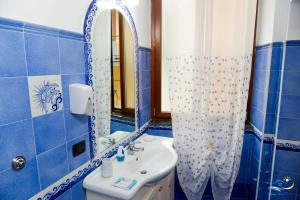 a blue tiled bathroom with a sink and a mirror at Holiday House Piccirillo in Vietri sul Mare